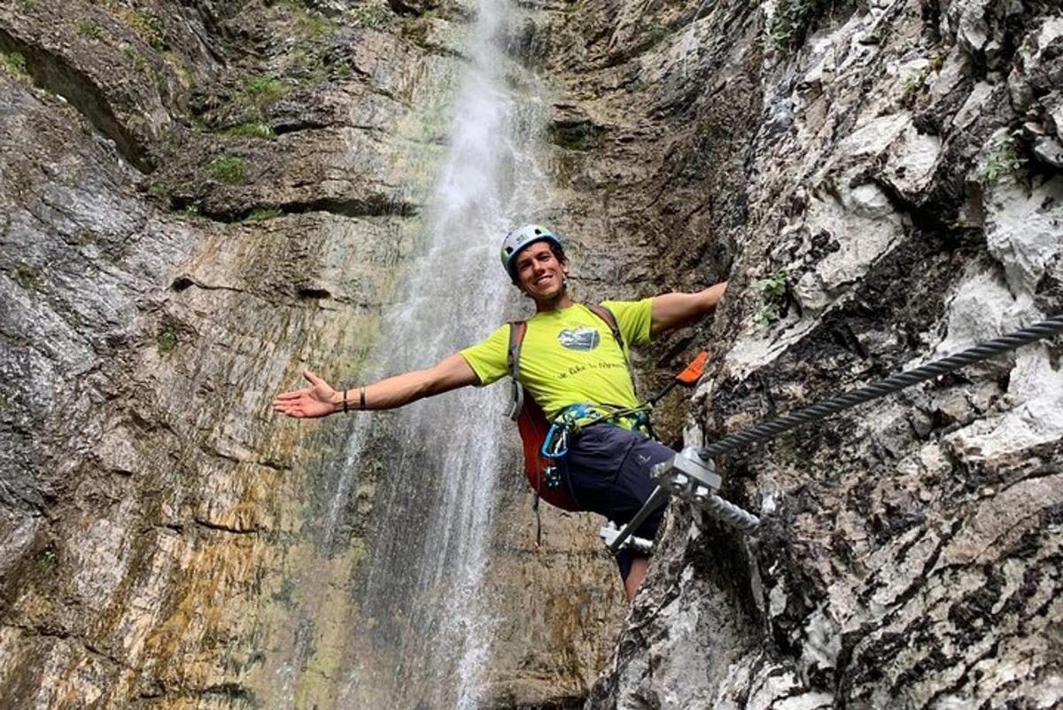 um homem está escalando uma parede de rocha em frente a uma cachoeira