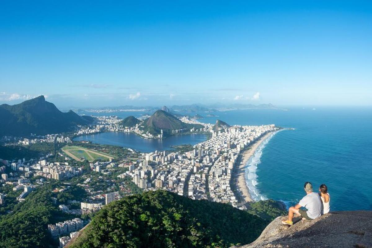 um casal sentado no topo de uma montanha com vista para a cidade