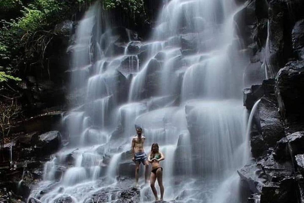 dua wanita berdiri di hadapan air terjun