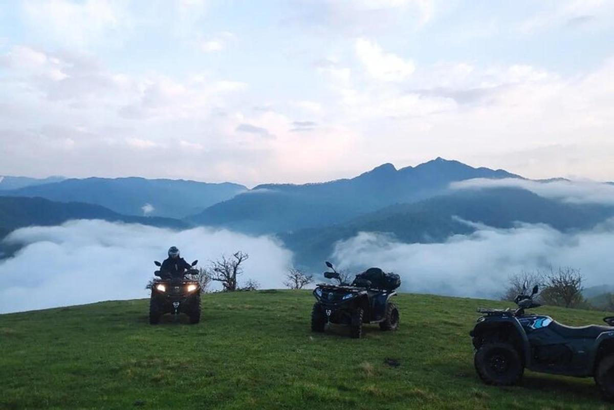 dues persones que condueixen motocicletes en un turó herbós amb muntanyes