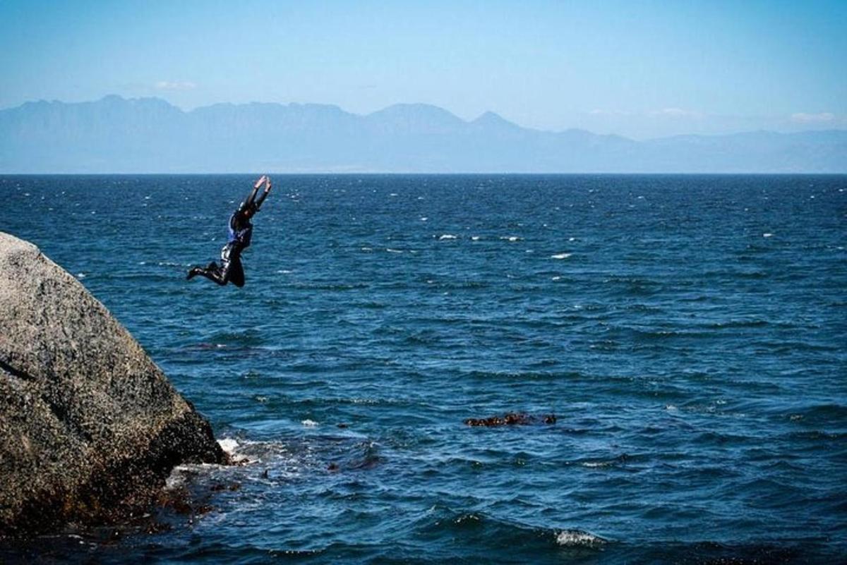 una persona che salta da una roccia nell'oceano
