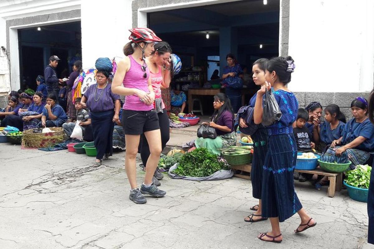 a group of people standing around a market with vegetables