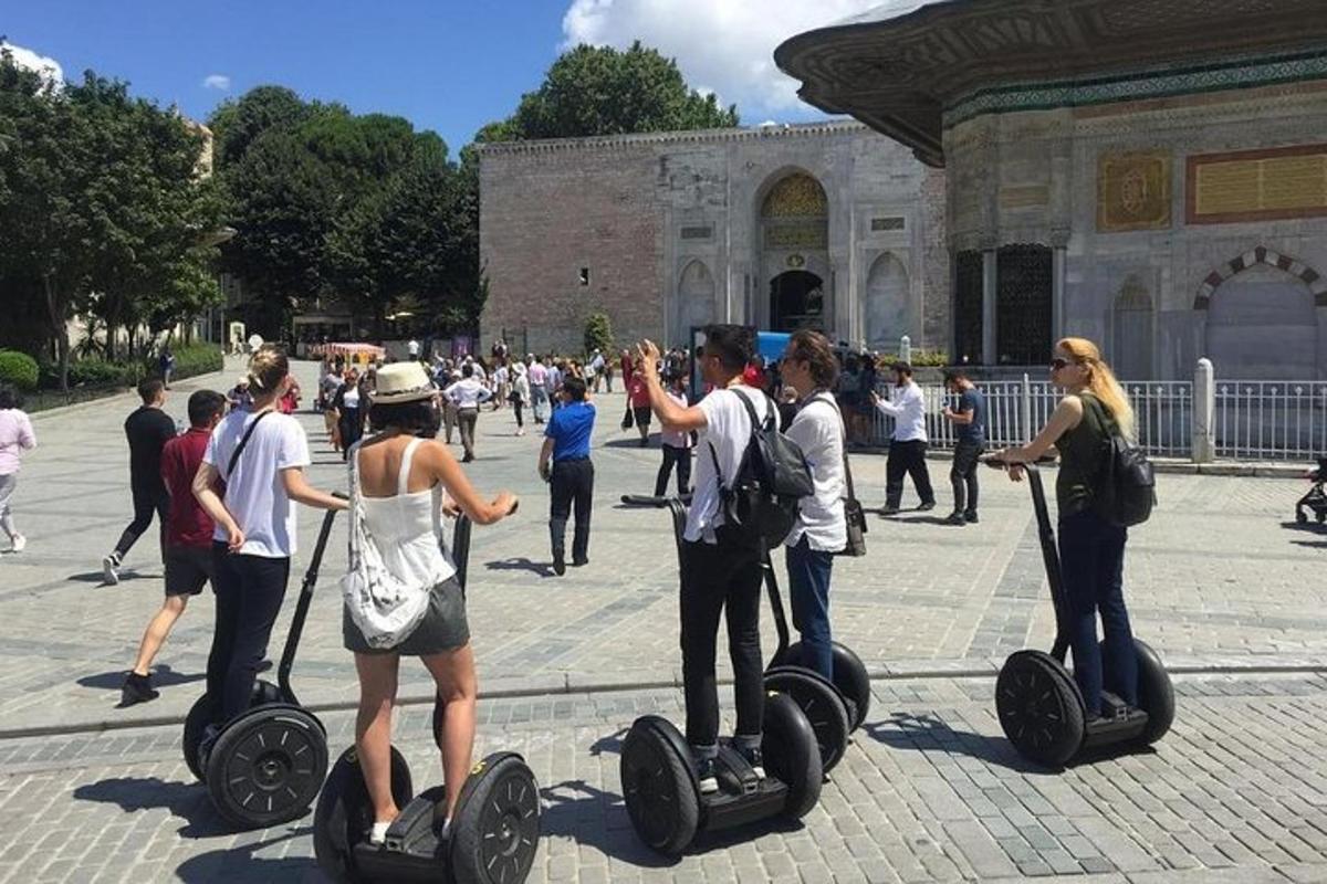 skupina lidí jedoucích na segwayích před budovou