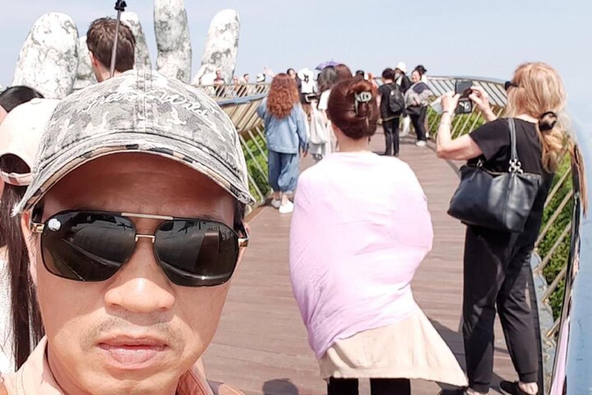 a man wearing a hat and sunglasses on a boardwalk
