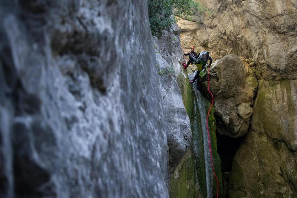 dua orang memanjat dinding batu di sebelah air terjun