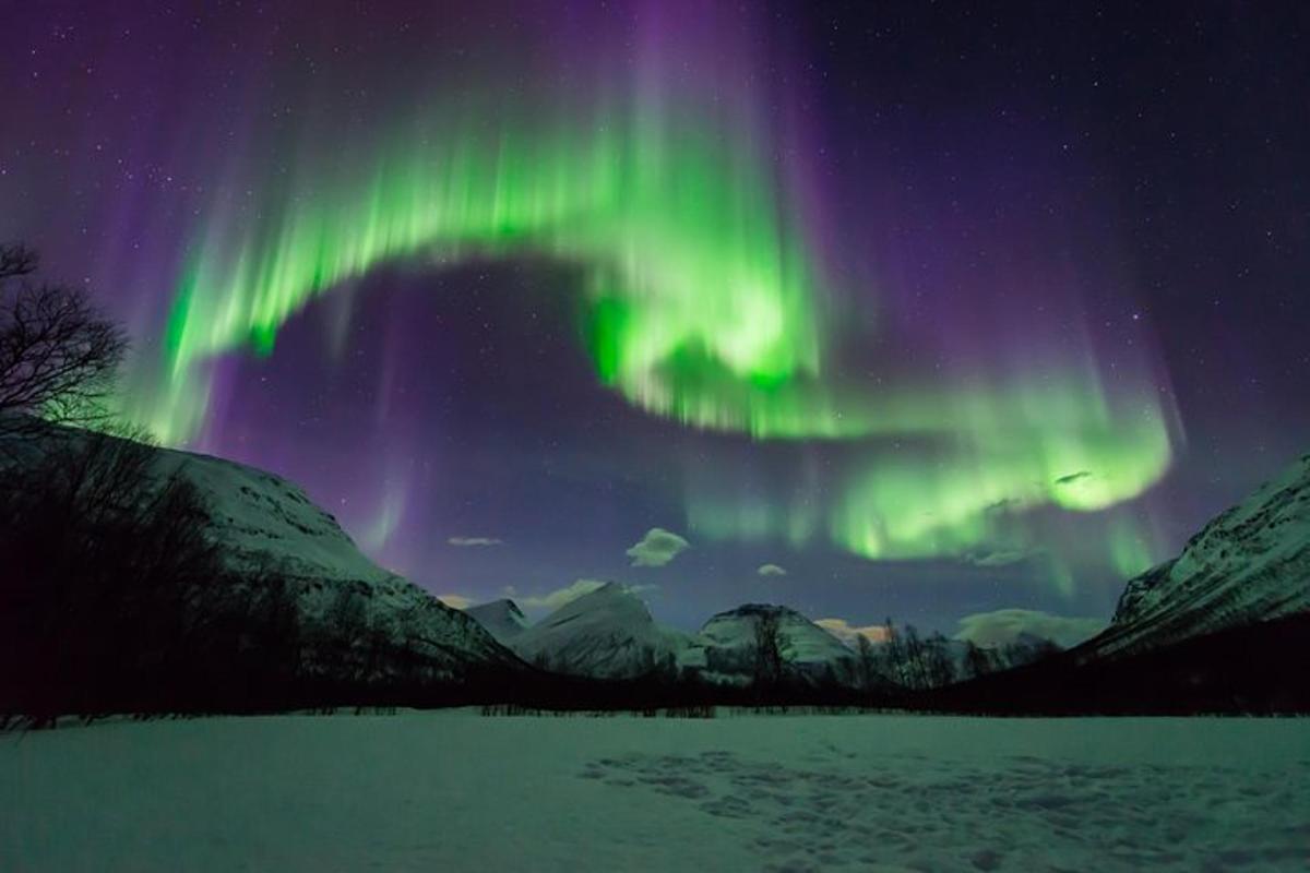 isang aurora sa kalangitan na may niyebe at mga bundok