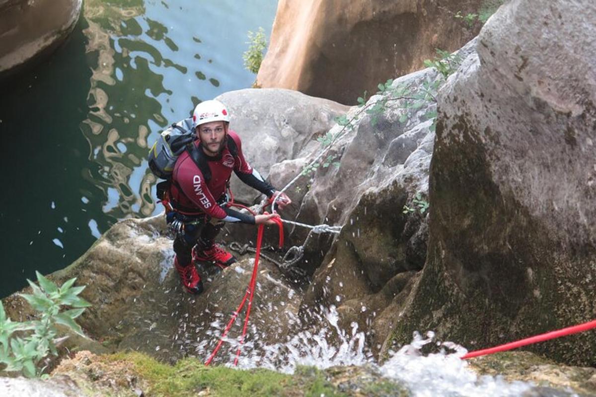 un home sobre una roca a l'aigua amb cordes