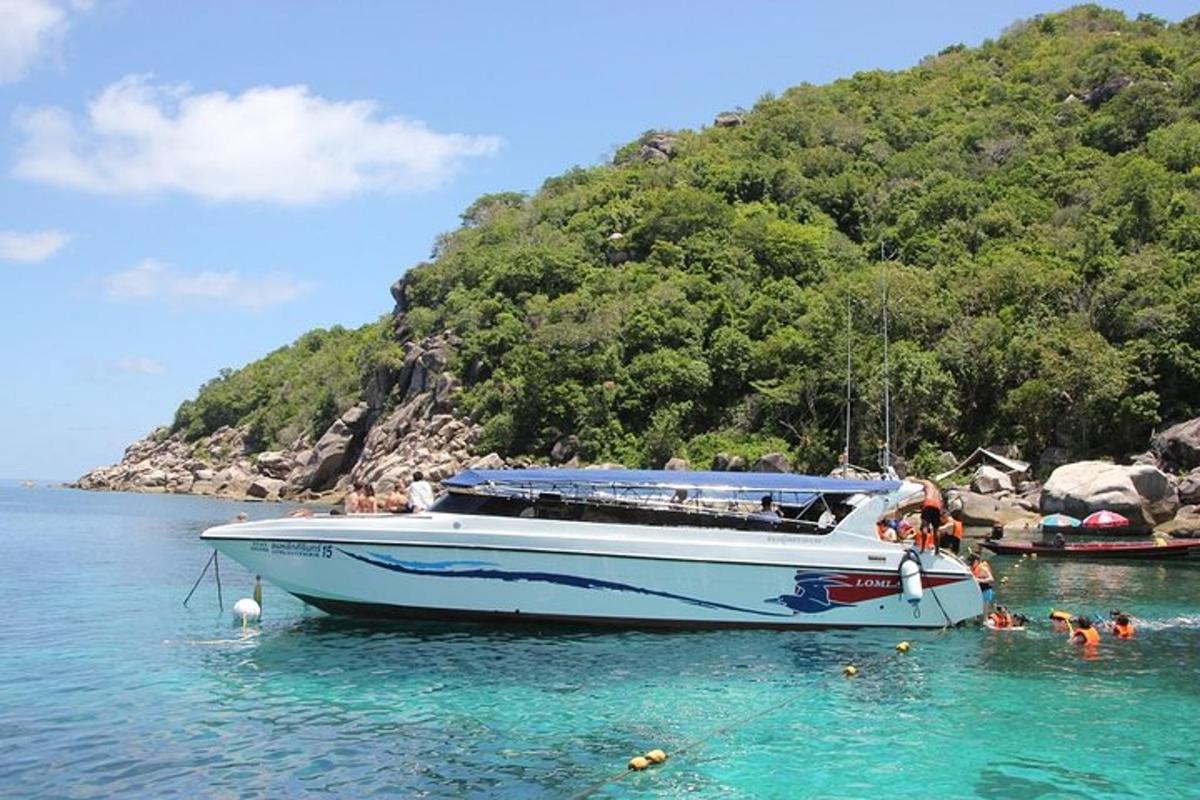 a white boat in the water next to a mountain