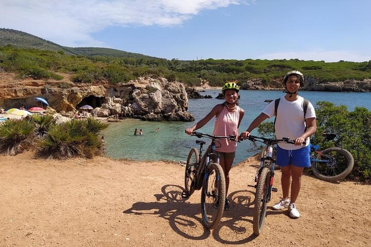 two people standing with their bikes on a beach