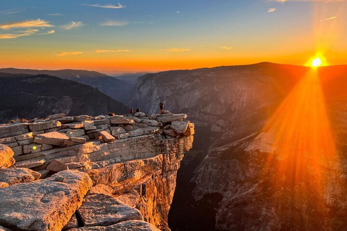 a person standing on the edge of a mountain at sunset