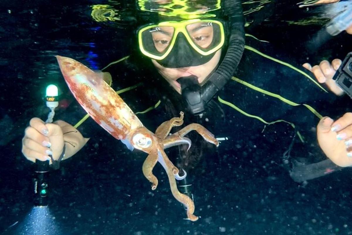 muž v potápěčské masce držící chobotnici