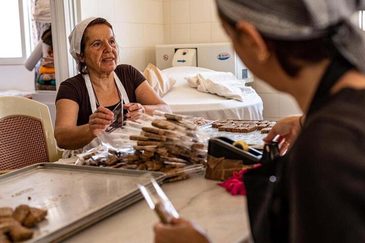 una donna anziana seduta a un tavolo che mangia pasticcini