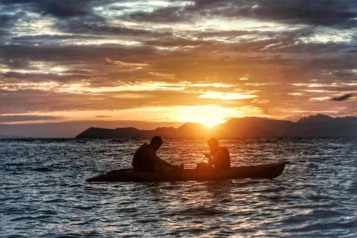 Dos personas sentadas en un kayak en el agua al atardecer