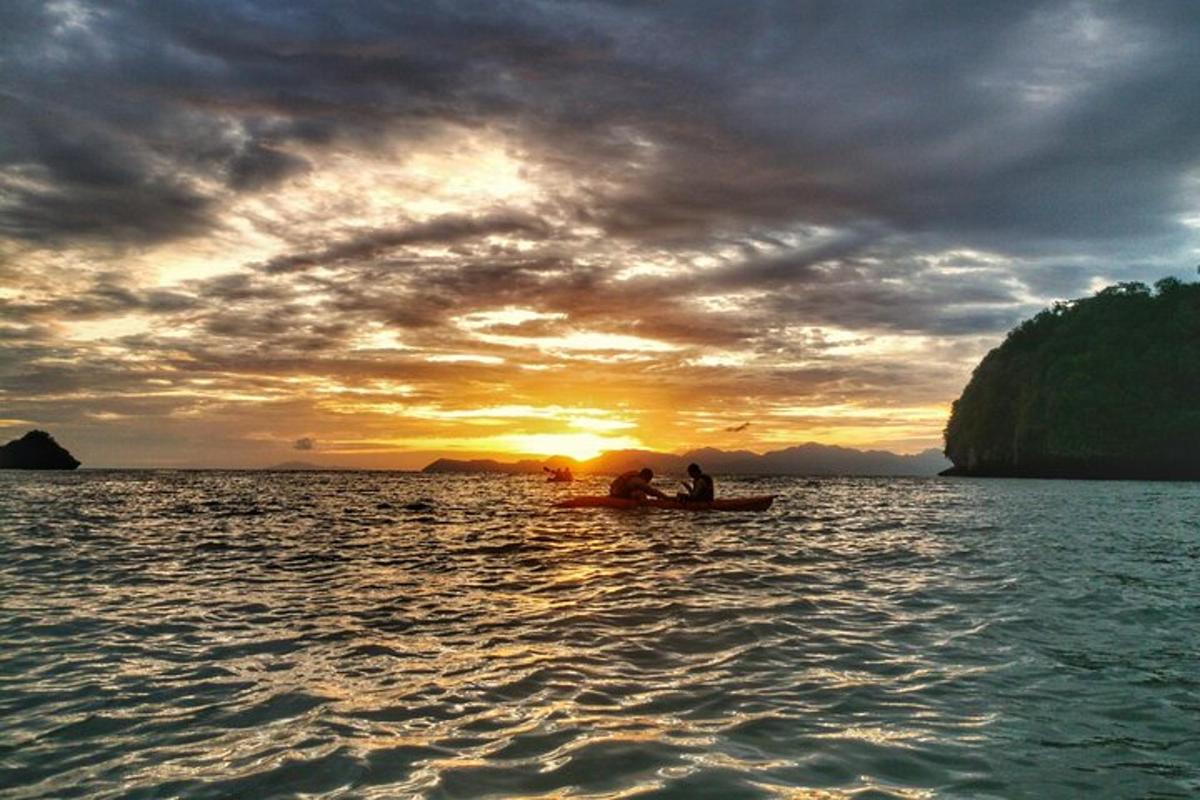 Dos personas en un barco en el agua al atardecer