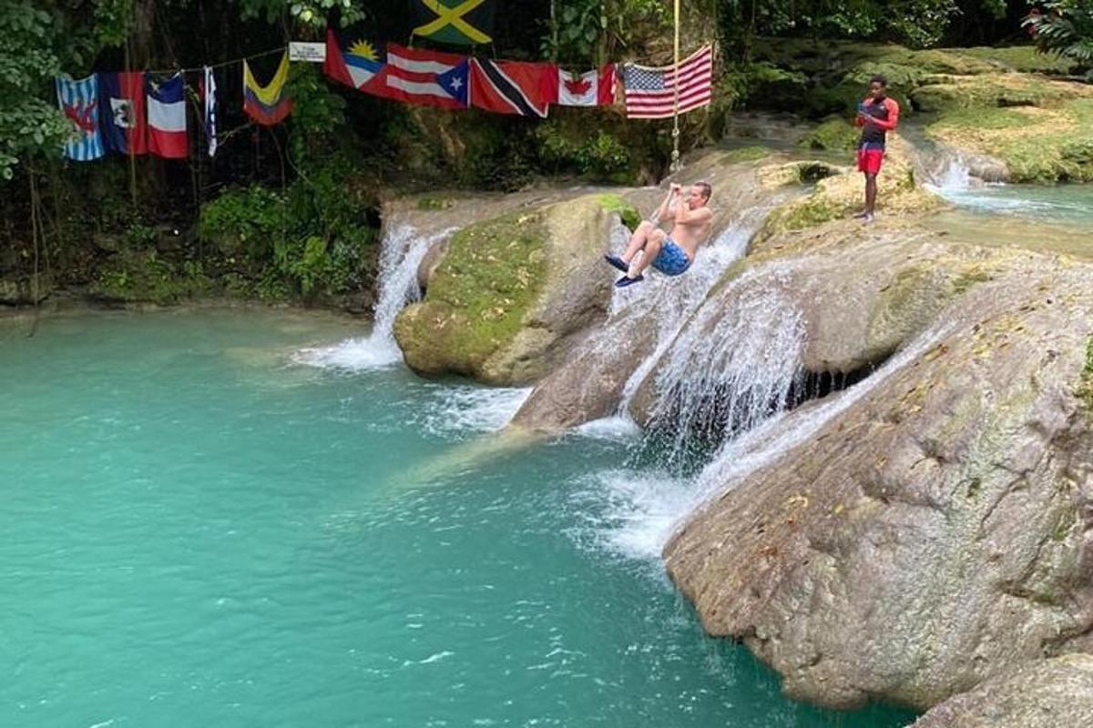 Un par de personas sentadas en unas rocas cerca de una cascada.