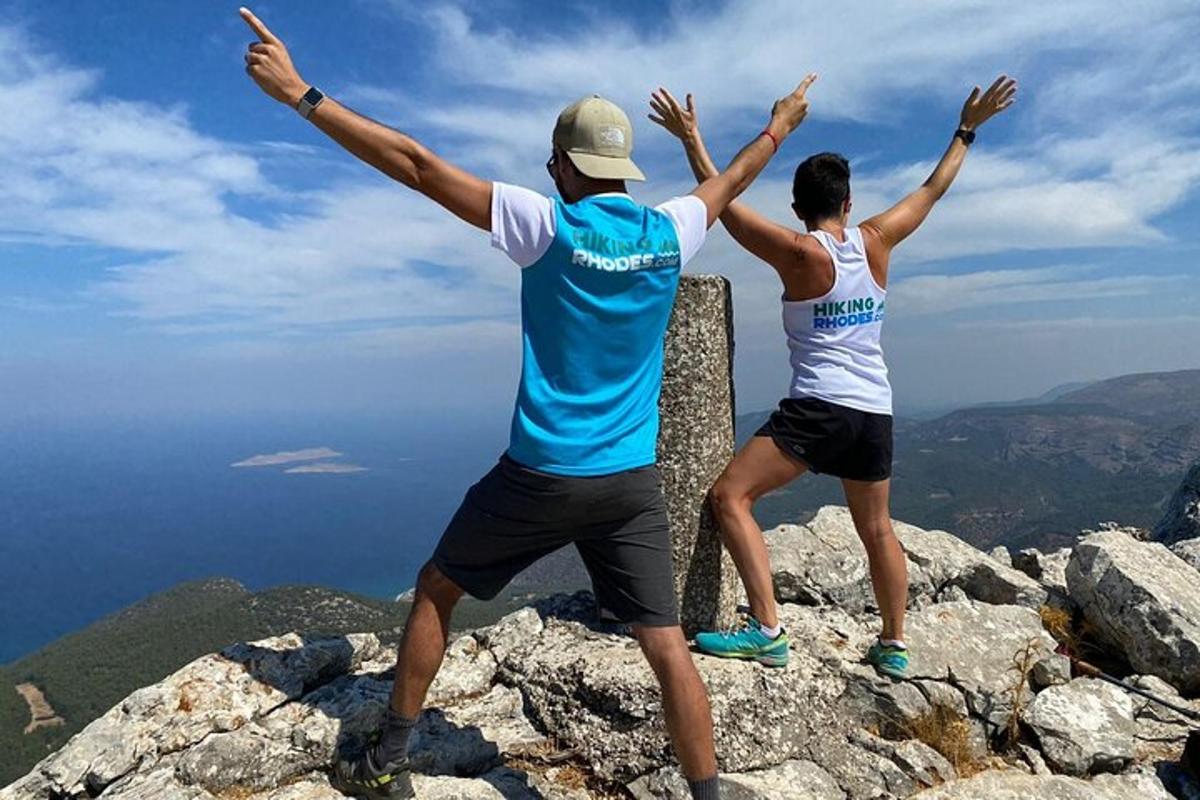 Dos personas paradas en la cima de una montaña con las manos en alto.