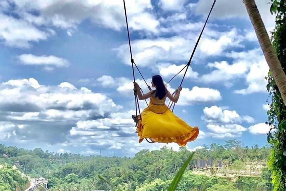 a woman in a yellow dress swinging on a swing