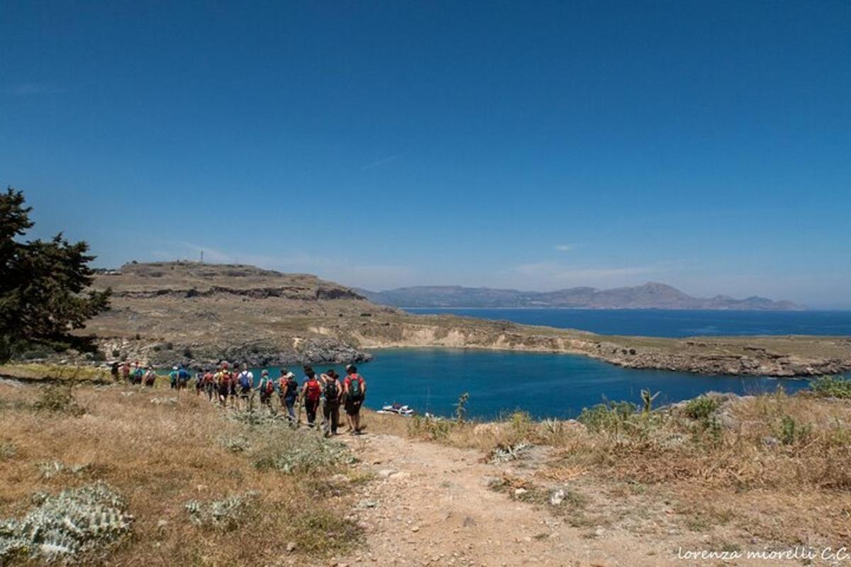 bir gölün yanındaki tepeye doğru yürüyen bir grup insan