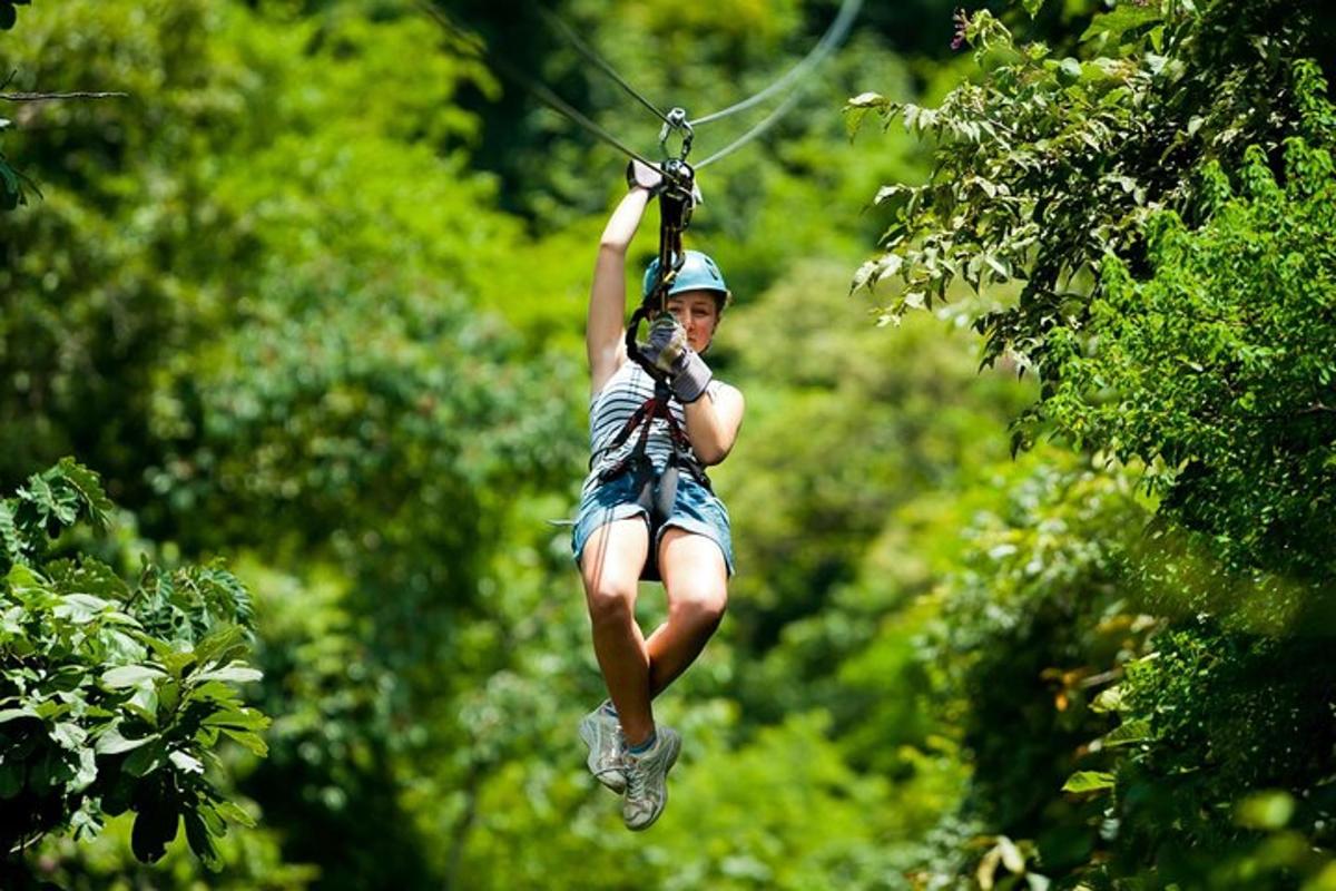 žena sa vezie na zipline v korunách stromov