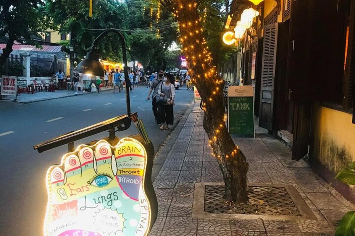 uma placa de guitarra ao lado de uma árvore na calçada