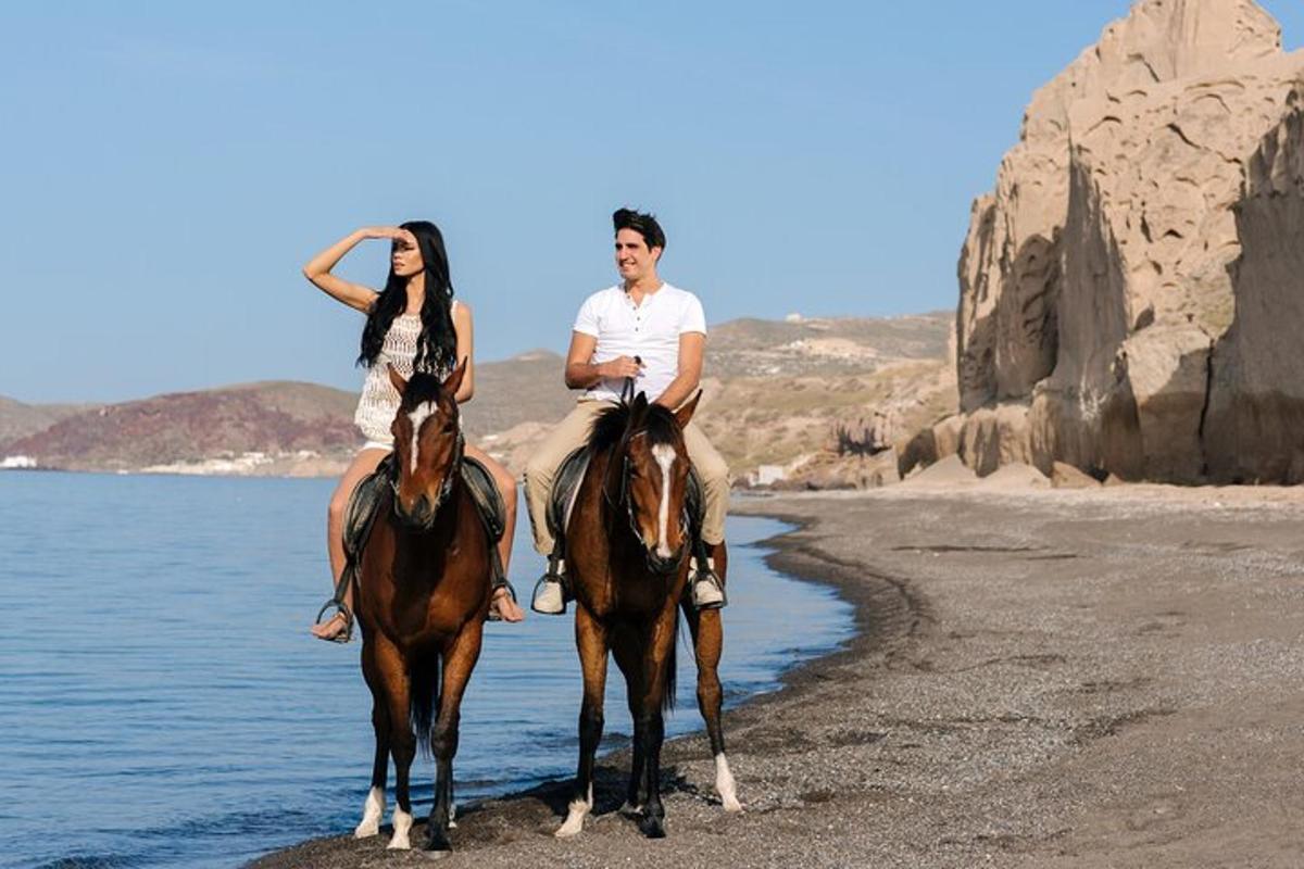 a man and a woman riding horses on the beach