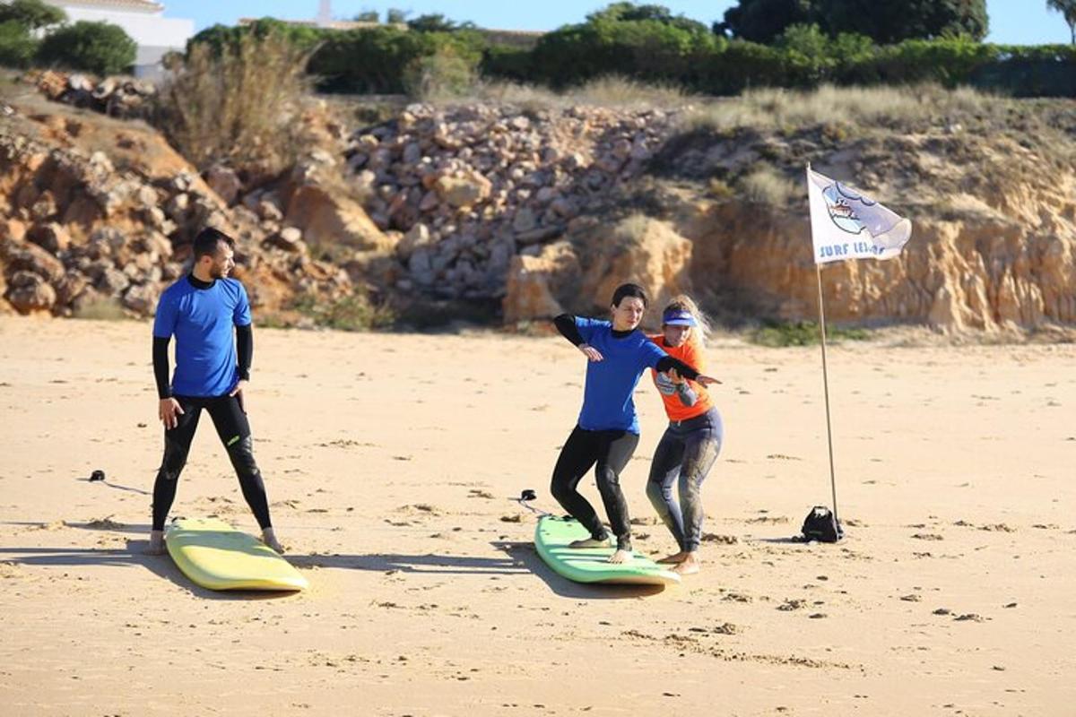 Tre personer står på surfbrætter på stranden