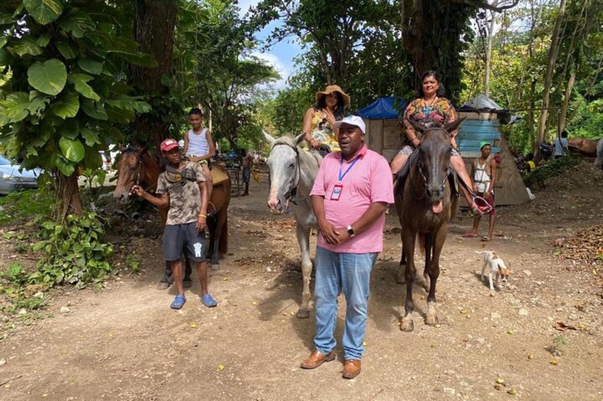 um homem em pé ao lado de um grupo de pessoas cavalgando