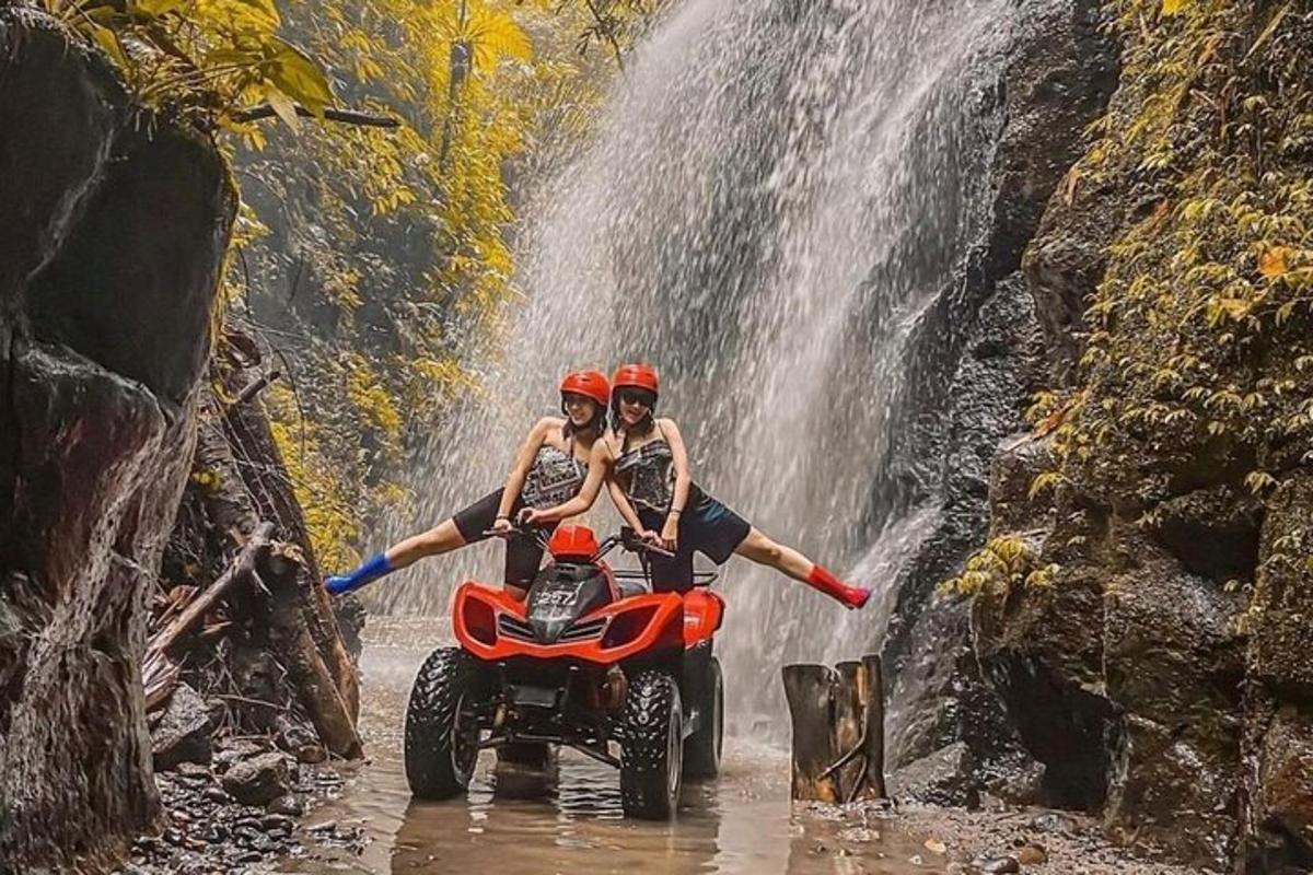 duas pessoas em um quadriciclo em frente a uma cachoeira