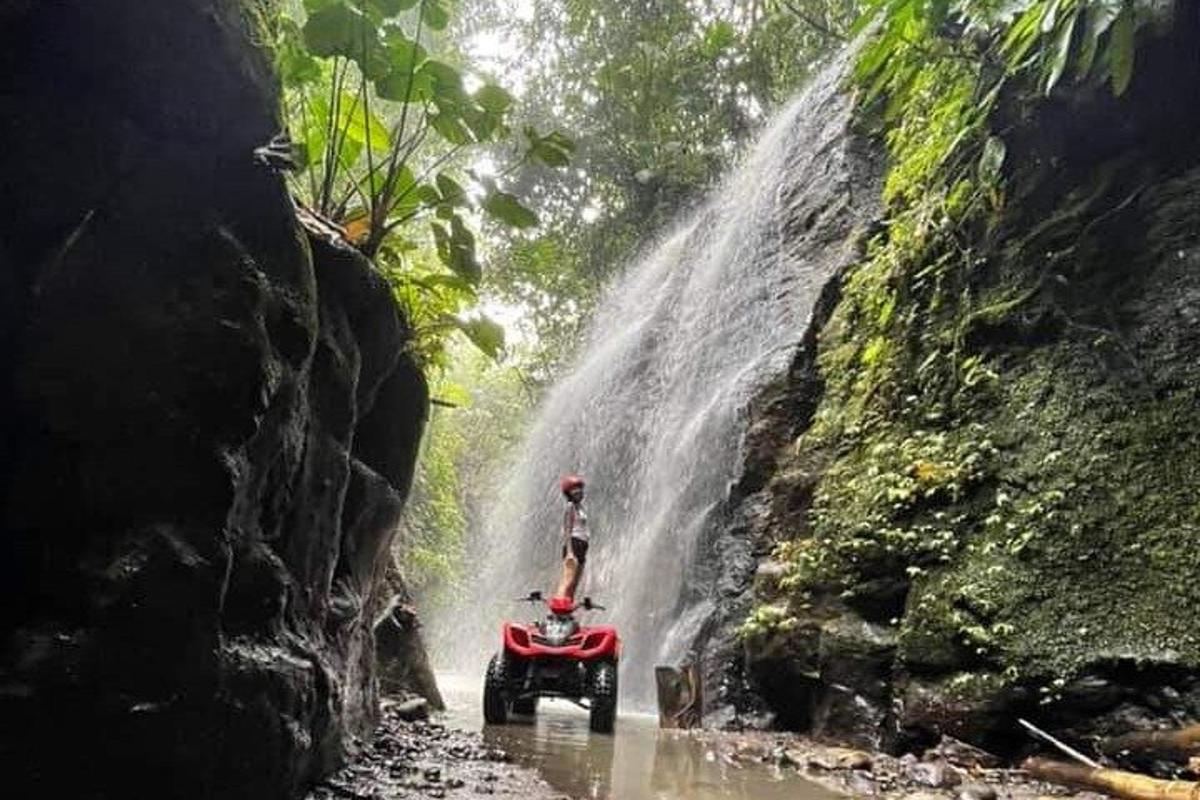 uma pessoa em um quadriciclo em frente a uma cachoeira