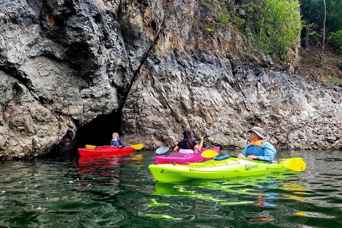 tre persone in kayak sull'acqua vicino a una grotta