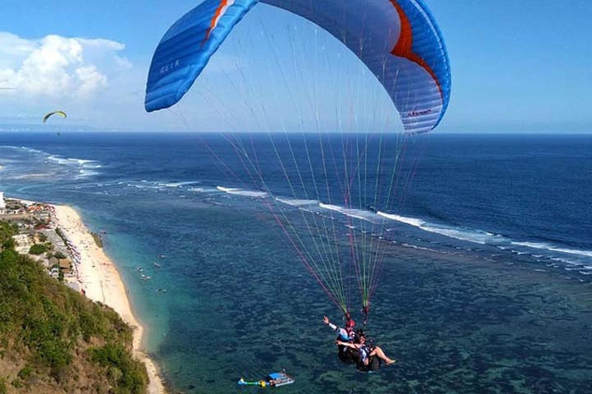 a person riding a parachute over the ocean