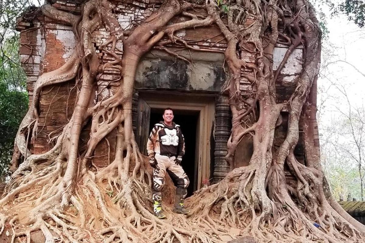 seorang lelaki berdiri di ambang pintu bangunan dengan akar pokok
