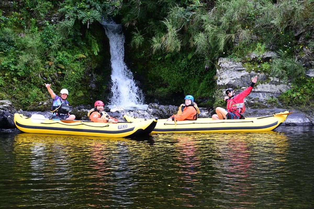 un gruppo di persone in kayak su un fiume con una cascata