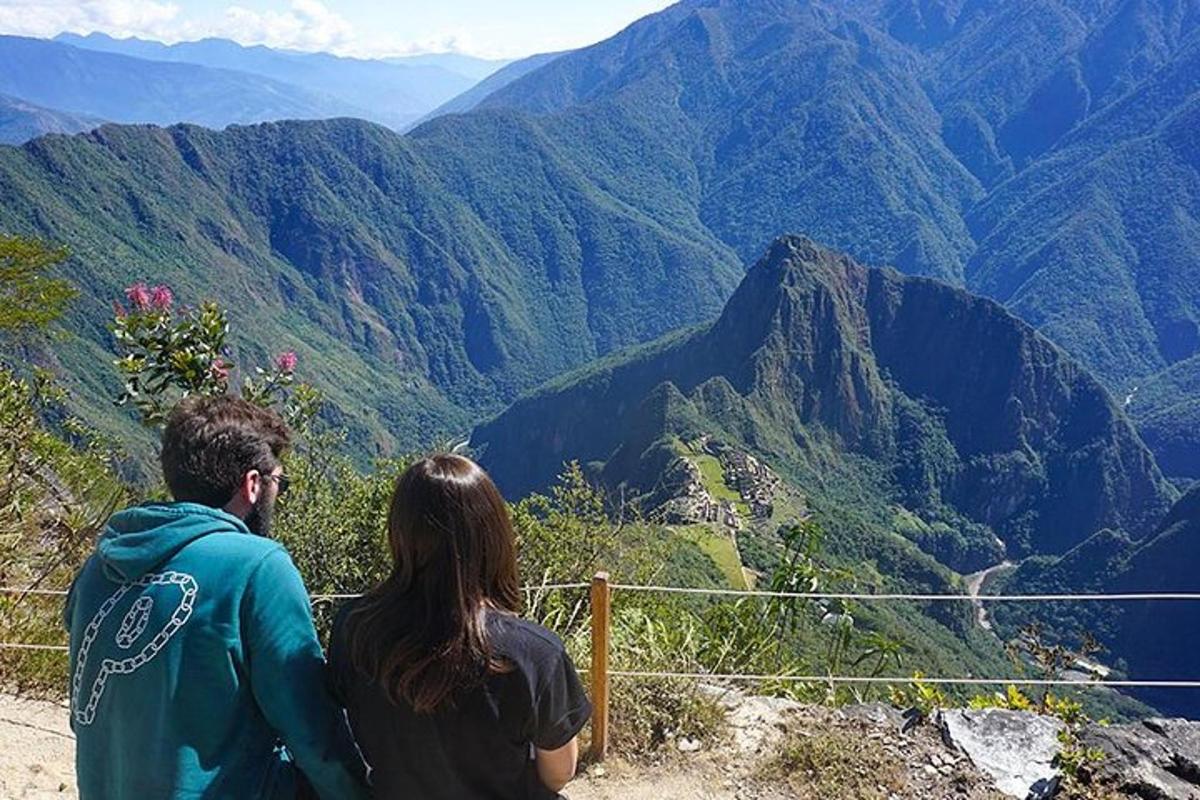 un uomo e una donna seduti su una sporgenza che guardano le montagne