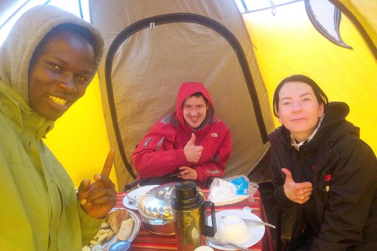 three people sitting at a table in a tent