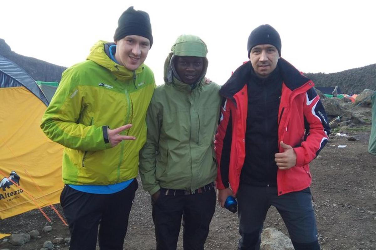 a group of three men standing next to a tent