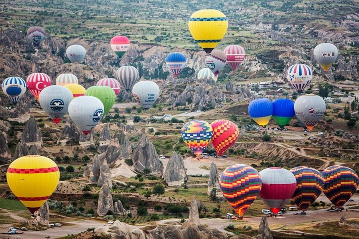 un munt de globus aerostàtics de colors volant sobre una muntanya