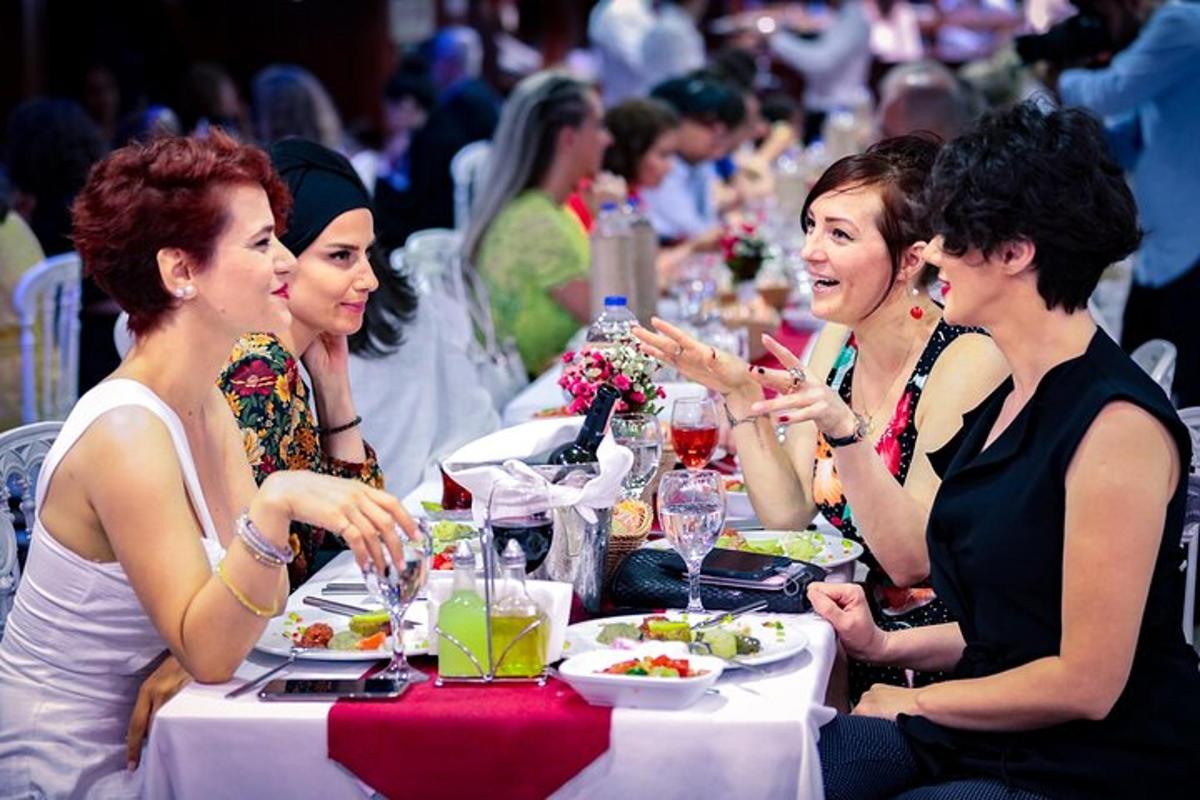 een groep vrouwen die aan een tafel zitten en eten