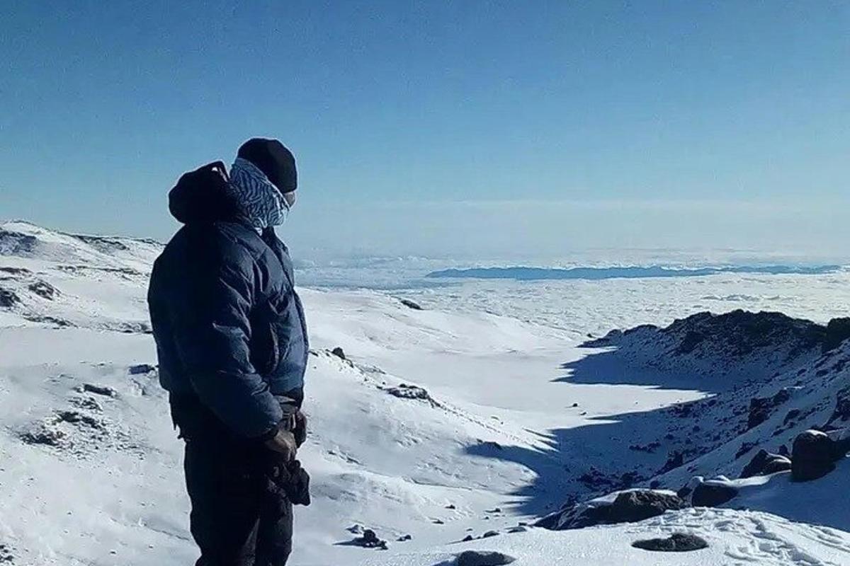 um homem em pé no topo de uma montanha coberta de neve