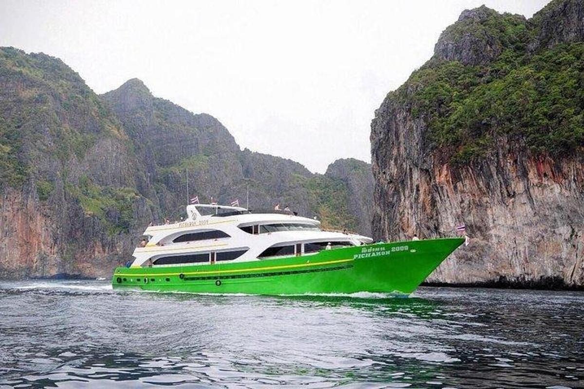 un bateau vert et blanc dans l'eau près des falaises