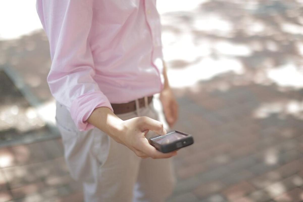 osoba držící v ruce mobilní telefon