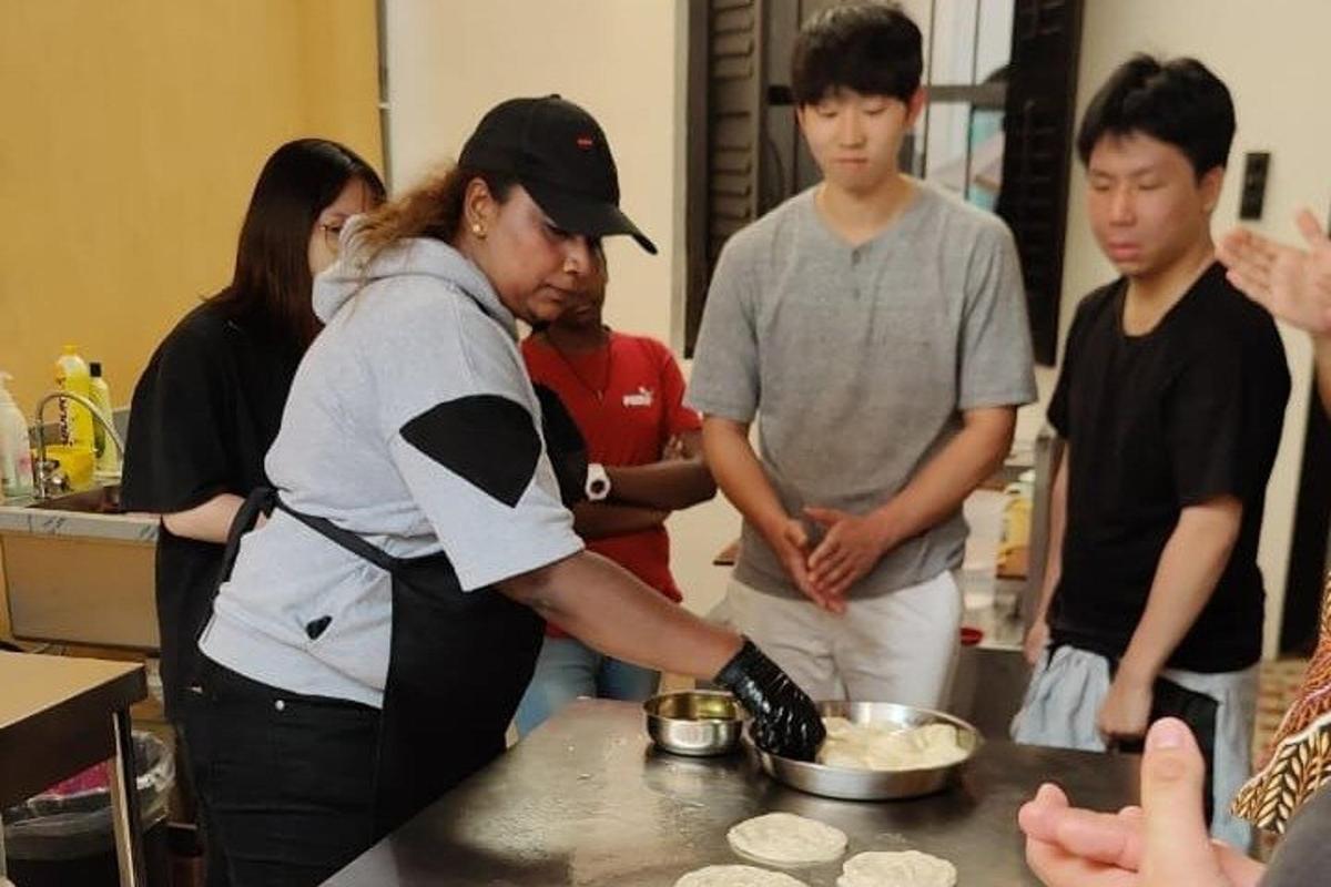 一名妇女与其他人一起在厨房准备食物