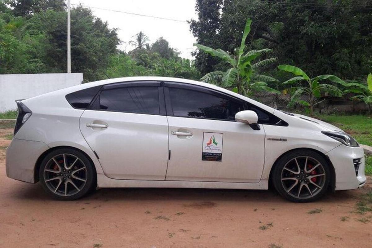 sebuah mobil putih terparkir di jalan tanah