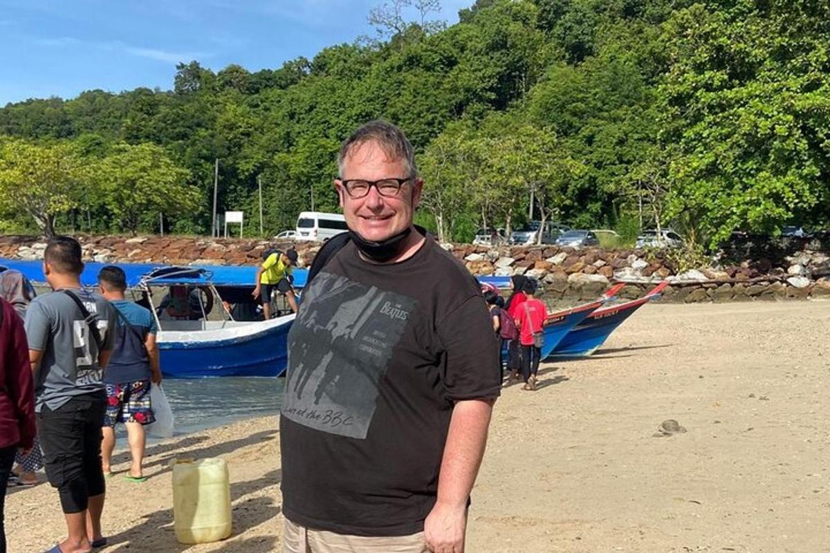 en mann som står på en strand med en gruppe mennesker