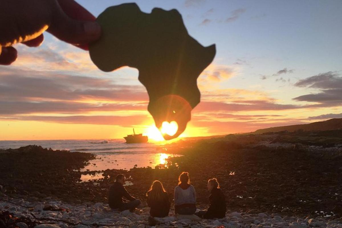 a group of people sitting on the beach watching the sunset