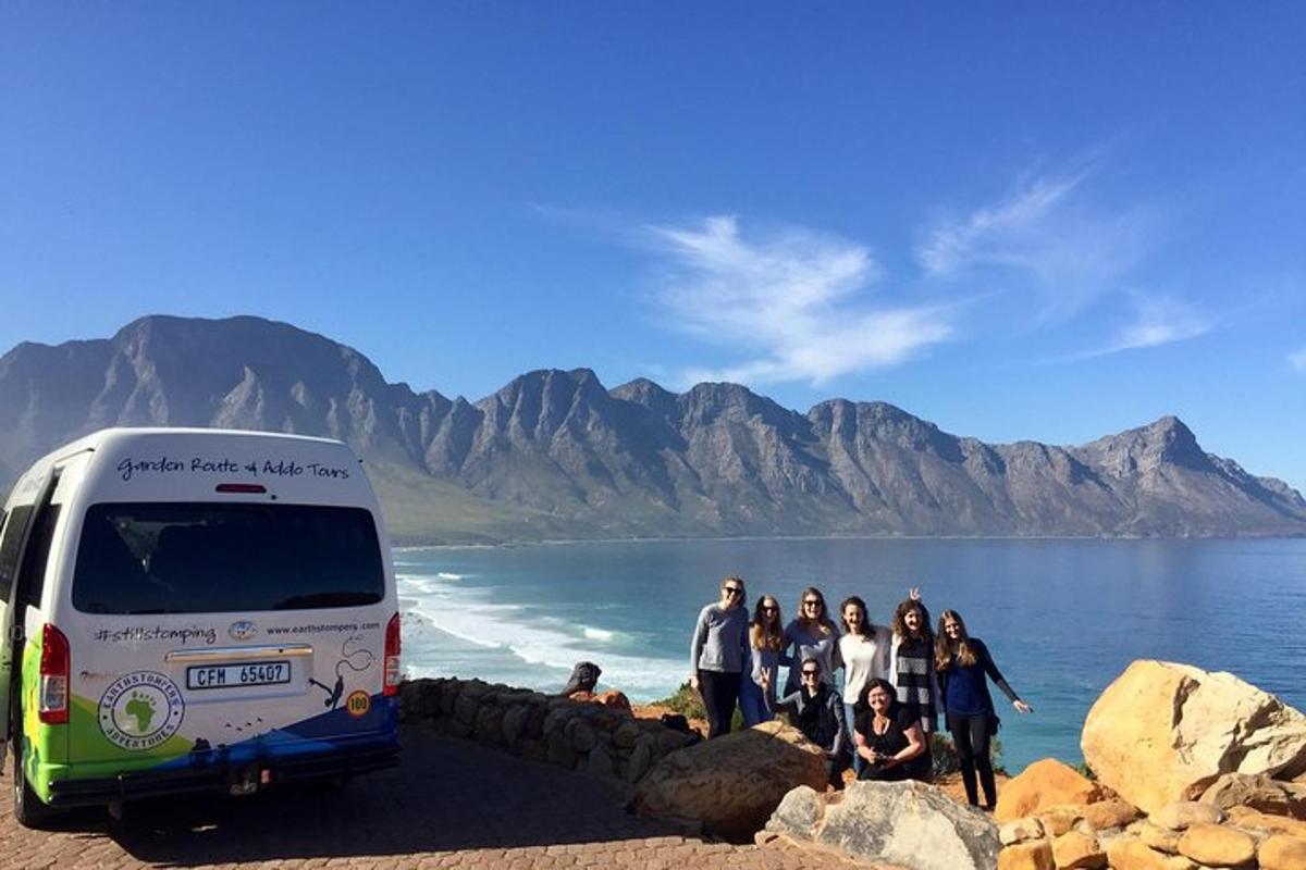 a group of people standing next to a bus on the beach