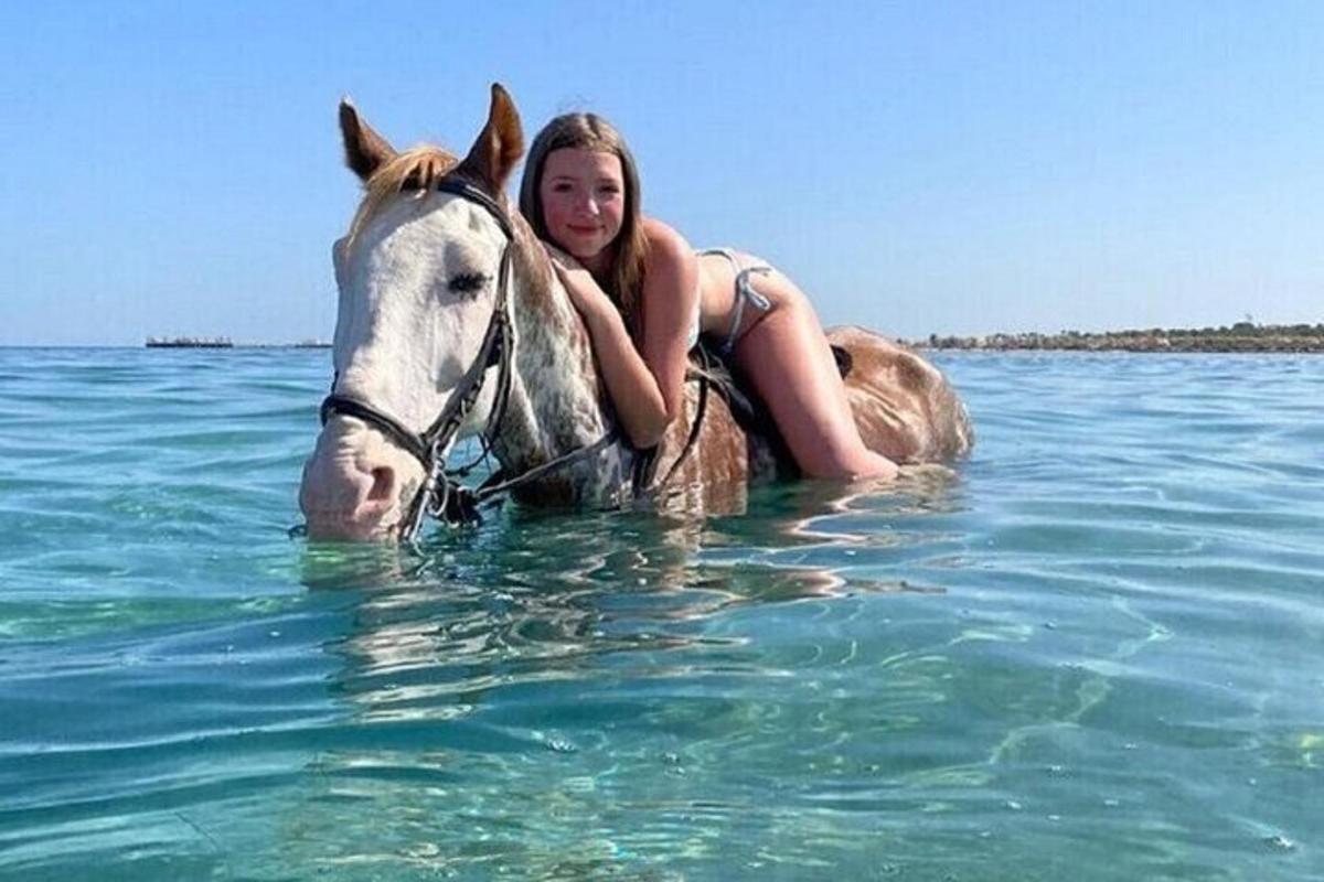 mladá dívka jedoucí na koni ve vodě