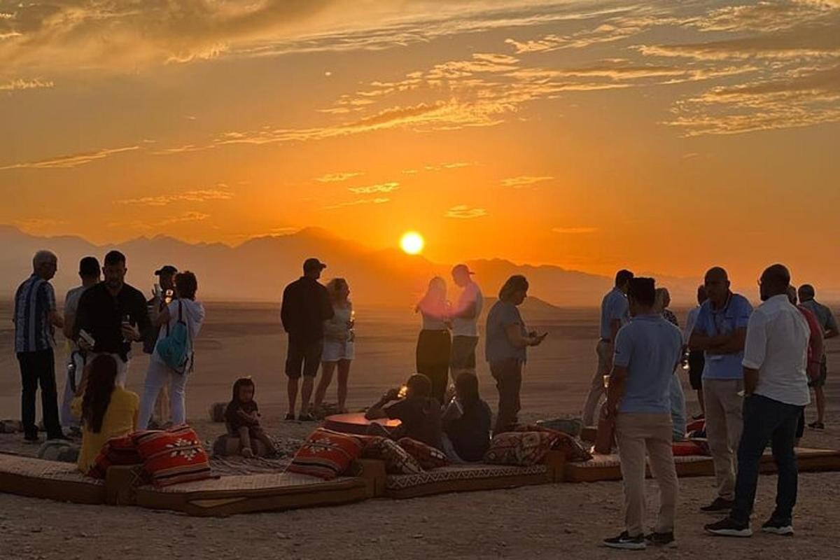 a group of people standing on the beach watching the sunset