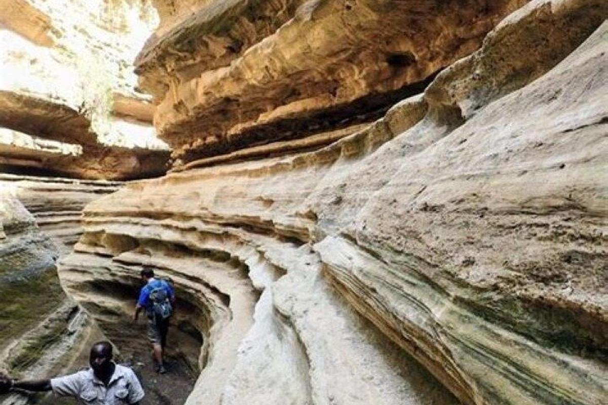 zwei Menschen gehen durch eine Schlucht mit Felsen