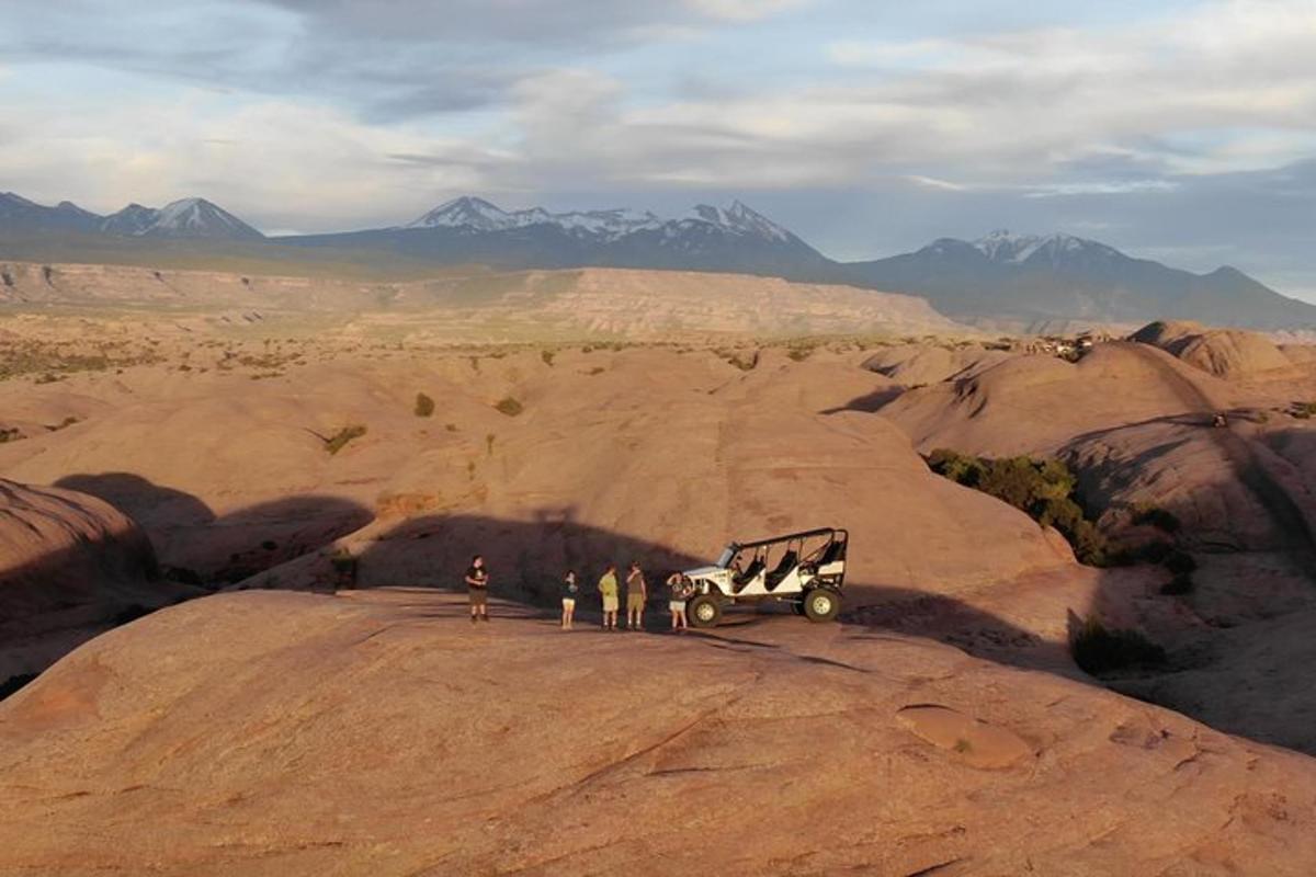 a group of people standing next to a jeep in the desert